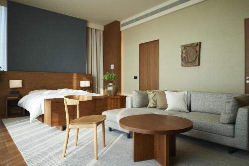 深圳深圳无印良品酒店的酒店客房配有床、沙发和桌子。