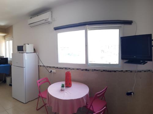 内坦亚Beau 2 pièces et Beau studio clair en plein centre ville Netanya的配有带粉红色椅子的桌子和电视的客房