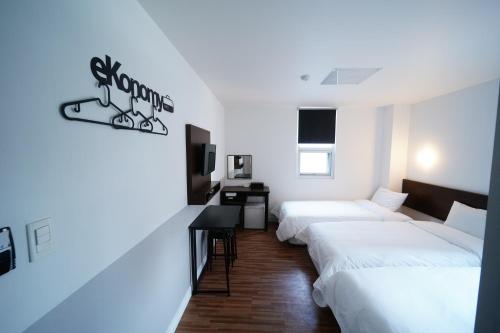 釜山Ekonomy Haeundae Hostel的酒店客房设有三张床和一张书桌