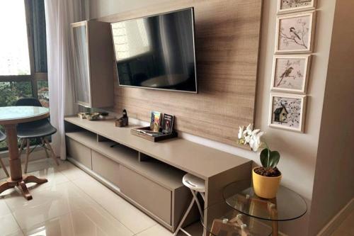 累西腓Apartamento com estilo e conforto的一间设有一张桌子的房间,墙上有一台电视机
