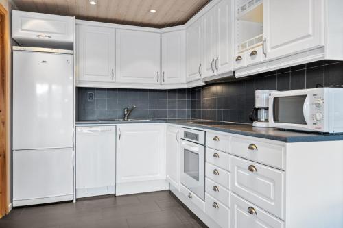波多Idyllisk sjøhus på Naurstad的白色的厨房配有白色的橱柜和微波炉