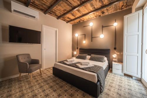 皮佐Palazzo Paladini - Luxury Suites in the Heart of the Old Town的一间卧室配有一张床和一把椅子
