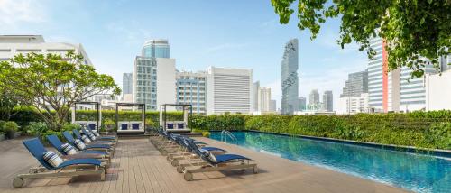 曼谷Le Meridien Bangkok的游泳池旁的一排躺椅
