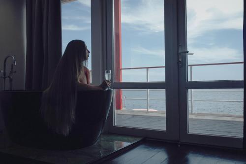 敖德萨Arkadia Beach Hotel的坐在窗户边喝一杯葡萄酒的女人