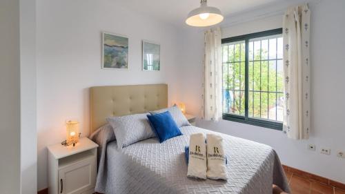弗里希利亚纳Apartamento Mirasierra 2 Frigiliana by Ruralidays的一间卧室配有一张带蓝色枕头的床和一扇窗户。