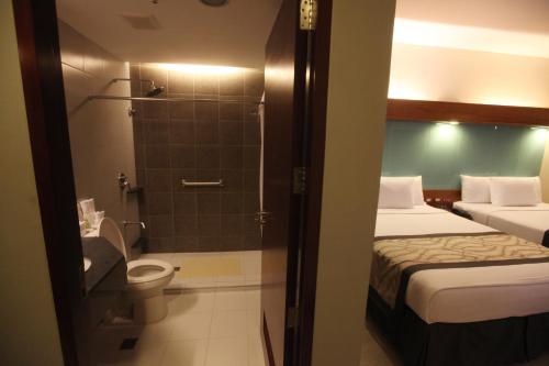 马尼拉Microtel by Wyndham UP Technohub的浴室设有两张床、淋浴和卫生间。
