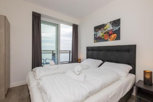 圣安娜兰Appartement Vista Maris, Havenweg 8-4, Sint Annaland的一间卧室配有一张带白色床单的大床