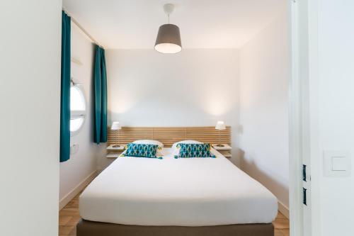 波城维多利亚花园波城公寓酒店的卧室配有带蓝色枕头的大型白色床