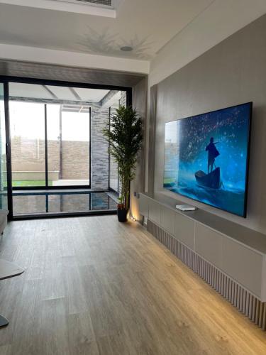阿吉曼AB Villa的客厅配有壁挂式大屏幕平面电视