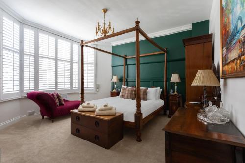 莫尔登Staycations Maldon的一间卧室配有一张天蓬床和一把椅子