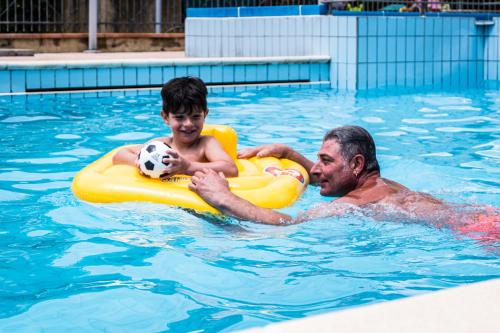 博尔焦韦雷齐萨利讷公寓式酒店的两个男子在游泳池里踢足球