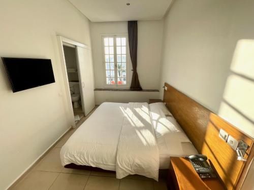 拉巴特吕泰斯酒店的卧室配有白色的床和电视。