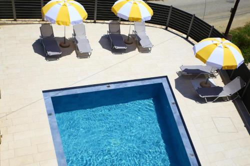 拉加纳斯Armonia Rooms的享有带两把遮阳伞和椅子的游泳池的上方景色