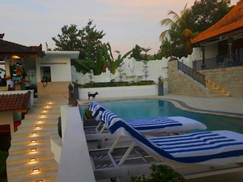 BanjarSoul Lodge Villa Lovina的一座房子旁的游泳池,配有两把躺椅