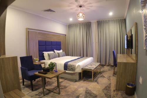 阿可贺巴Swat Olaya Hotel Apartments的酒店客房带一张床、一张桌子和椅子