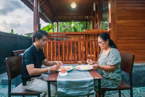 登巴萨Pondok Biu的坐在餐桌旁吃食物的男人和女人