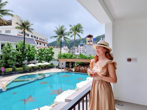 芭东海滩Sawaddi Patong Resort & Spa by Tolani - SHA Extra Plus的站在游泳池旁阳台的女人