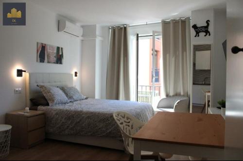 马拉加Luxury Estudio Malaga Centro的一间卧室配有一张床、一张桌子和一个窗户。