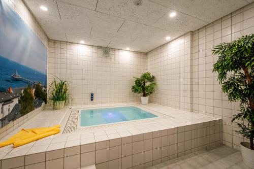 黑灵斯多夫沃尔德酒店的白色瓷砖的植物间里的一个游泳池