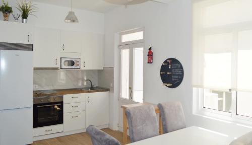 费罗尔Apartamento en centro de Ferrol的厨房配有白色橱柜和桌椅