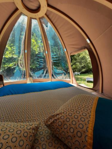 米奥La Wigwam Bleu du Domaine du Pas de l'âne的帐篷内的一张床位,设有两个窗户