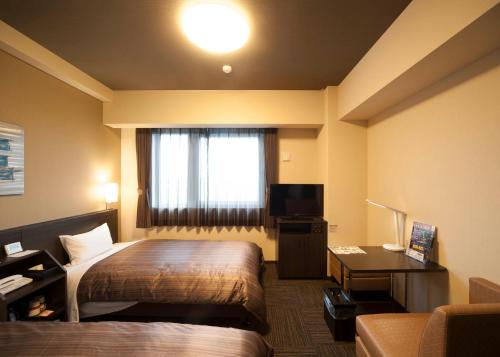 小野小野路线酒店的配有一张床、一张书桌和一扇窗户的酒店客房