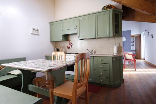 帕索罗莱LA PULCE INNEVATA - Dolomiti Affitti的厨房配有绿色橱柜和桌椅