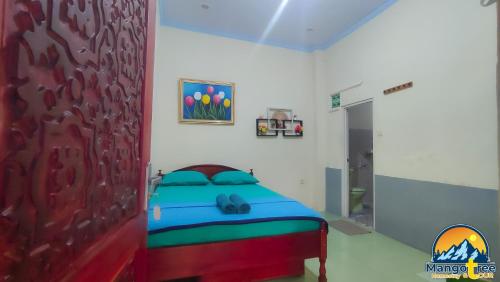 外南梦Mango Tree Homestay & Ijen Tour的卧室配有一张床,墙上挂有绘画作品