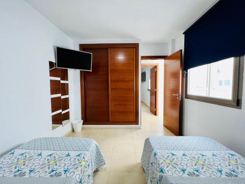 大加那利岛拉斯帕尔马斯Apartamento Muelle Deportivo的一间卧室配有两张床和电视。