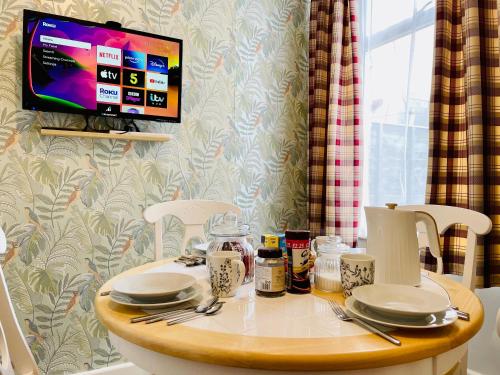 朴次茅斯Clive Crest house的一张桌子,上面有盘子和餐具,还有一台电视