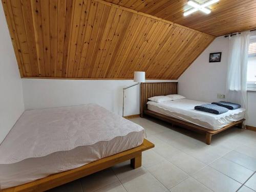 南海郡Namhae German Village Johannes的一间卧室设有两张床和木制天花板
