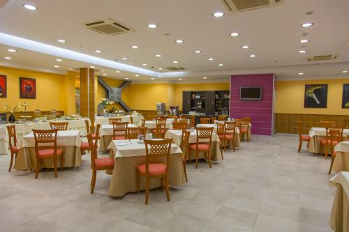 那不勒斯菲尤特拉会议中心酒店的餐厅设有白色的桌椅和紫色的墙壁