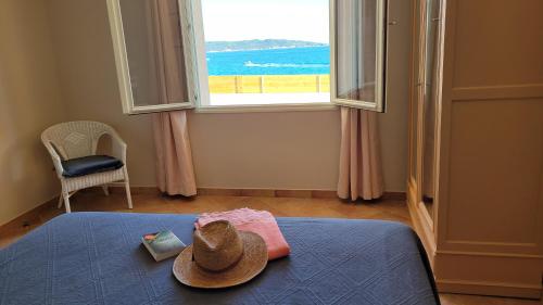 耶尔Villa en bord de mer face à l'Ile de Porquerolles的窗户间床上的一顶帽子