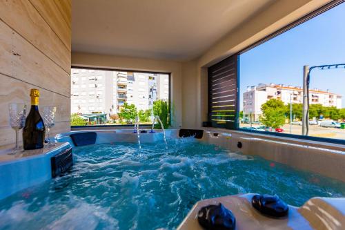 扎达尔Mrak Zadar Exclusive的热水浴池、一瓶葡萄酒和窗户