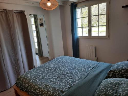ParnayAppartement RDC-Loire à vélo-Proche Saumur的一间卧室配有一张蓝色棉被和两个窗户。