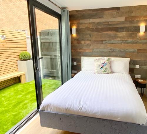 伯恩茅斯Coastline Retreats - Cloud9 Holiday Accommodation- 2 Bedroom self contained garden flat - Luxury bath, Netflix, Superfast Wifi, Parking included的一间卧室设有一张床和一个大窗户