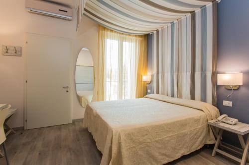 切塞纳蒂科Hotel Trieste的一间卧室设有一张床和一个大窗户