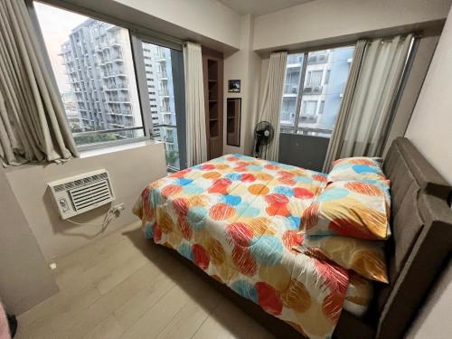 马尼拉Resorts World Condo的一间卧室配有一张带色彩缤纷的被子和窗户的床。