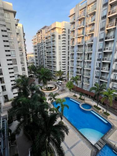 马尼拉Resorts World Condo的公寓大楼设有游泳池和棕榈树