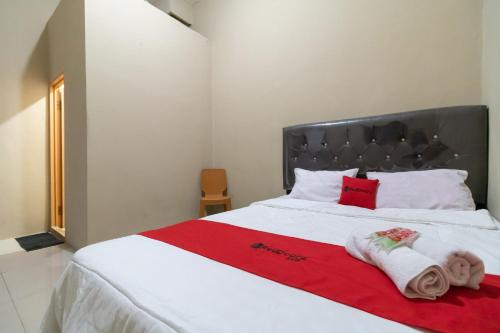 SukaramiRedDoorz near Palembang Trade Center 4的卧室配有白色床和毛巾