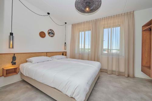 托尔恩Parc Maasresidence Thorn Apartments的卧室设有一张白色大床和两个窗户。