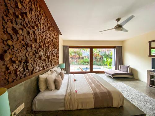 龙目岛库塔VILLA ASAM pool side的一间卧室设有一张床和石墙