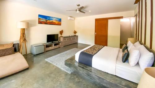 龙目岛库塔VILLA ASAM pool side的一间卧室配有一张大床和电视