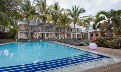圣吉尔莱班Hotel Exsel Alamanda的棕榈树建筑前的游泳池
