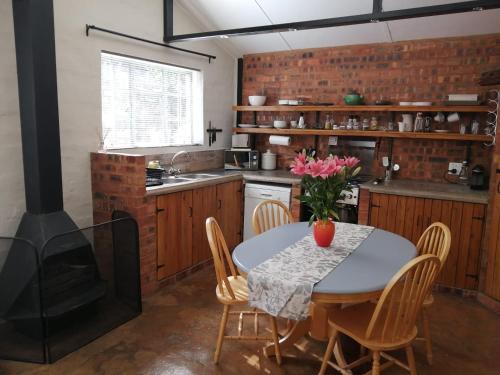 比勒陀利亚Wild Olive Cottage in Hartbeespoort的厨房配有桌椅和炉灶。