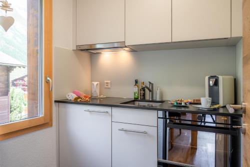 采尔马特乔利蒙特公寓酒店的厨房配有白色橱柜和黑色台面