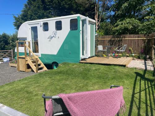 阿贝尔格莱Pant y Rhedyn Glamping and camping site的停在院子里的绿色白色拖车