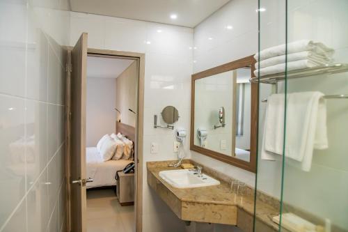 卡利Hotel Estancia Chipichape Cali的一间带水槽和镜子的浴室以及一张床