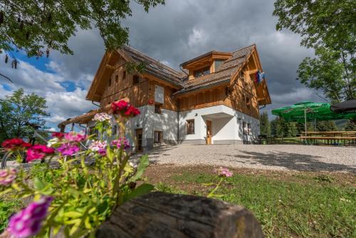 Srednja Vas v BohinjuPlaninska koča na Uskovnici的一座带木屋顶和鲜花的房子