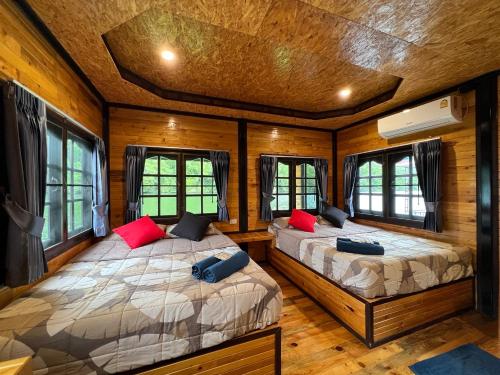 Tha KradanPhu Naphat Resort的配有木墙和窗户的客房内的两张床